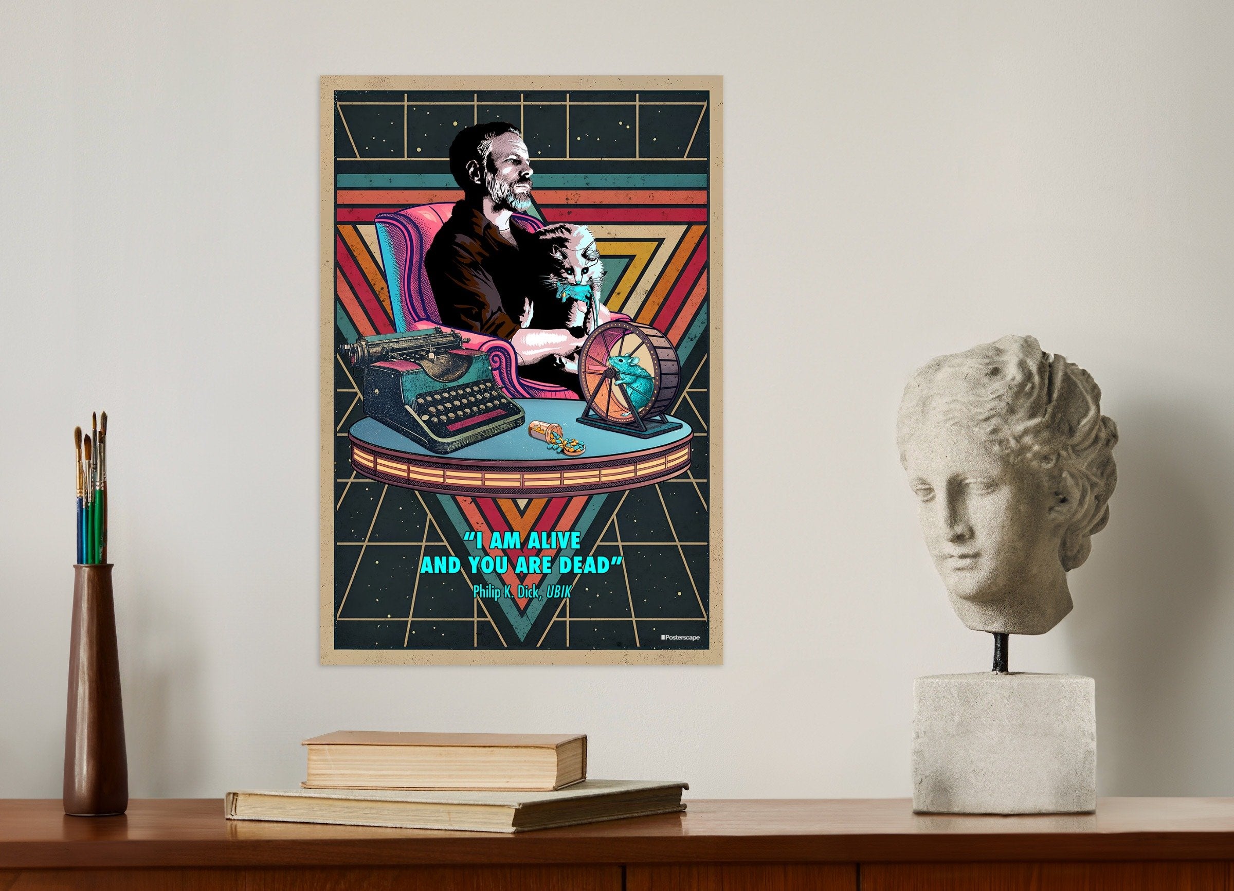 Framed poster of a character with a typewriter on a wall above a desk with books and a sculpture.