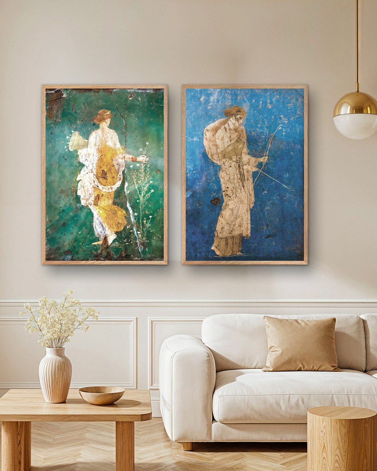 Conjunto de 2 pósters de frescos romanos, Flora y Artemisa, con marcos de madera natural sobre un sofá en un salón